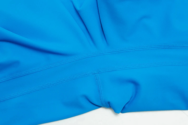 Close-up of blue high-waist yoga leggings fabric, showcasing elastic and breathable LYCRA material for optimal performance and comfort.